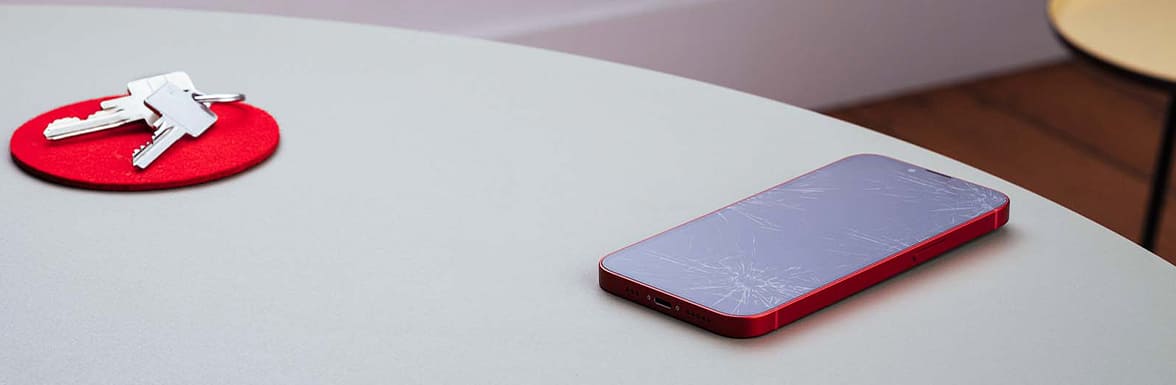 A mobile phone with a smelled display lies on the table.
