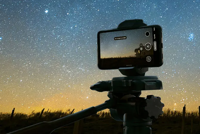 The mobile phone is attached to the tripod and pointed towards the night sky.