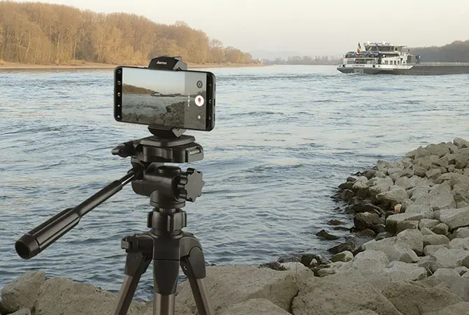 The mobile phone is attached to the tripod and pointed at the surface of the water.