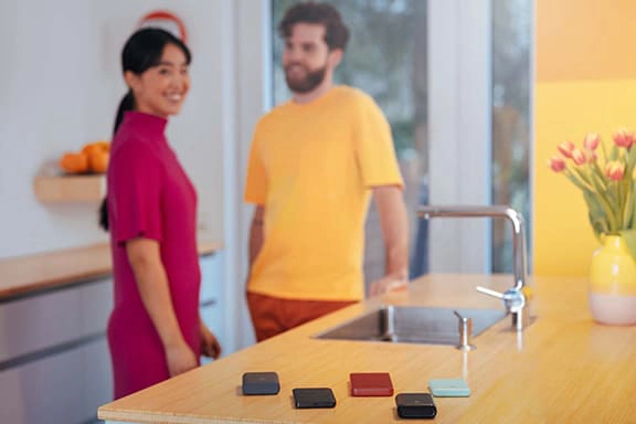 Several power banks lie on a counter, cheerful people in the background