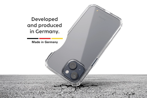 A smartphone is in a Hama mobile phone case and falls with the top corner onto hard asphalt - but the asphalt breaks, the smartphone remains intact. A white button reads ‘Developed and produced in Germany’ in black lettering.