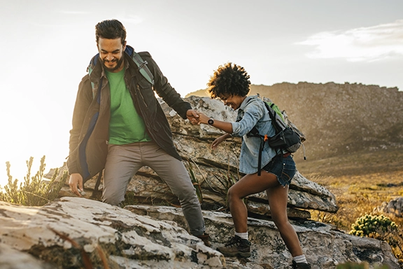 A couple hike over rocky hills. On the woman's wrist you can see the Hama Smartwatch "8900"