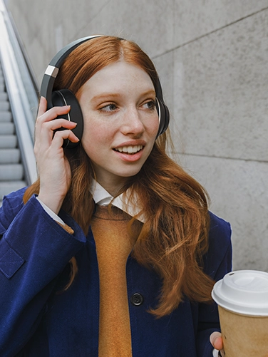 A woman wearing Bluetooth headphones is on her way to the underground station.