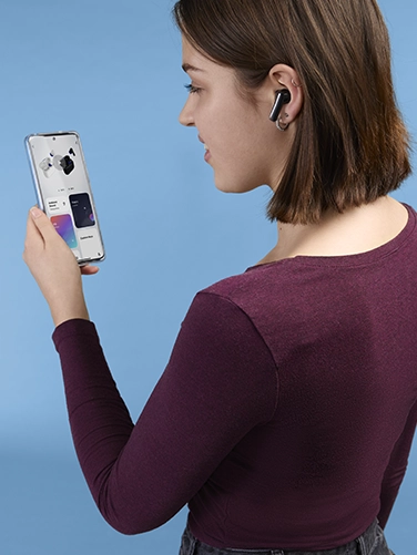 Young woman operating her smartphone and making settings on the Hama "Passion Clear II" Bluetooth® headphones