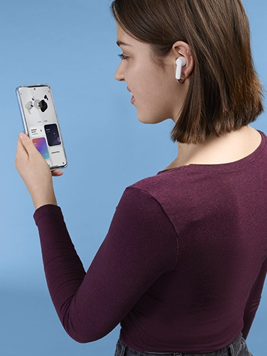 Young woman operating her smartphone and making settings on the Hama "Passion Clear II" Bluetooth® headphones