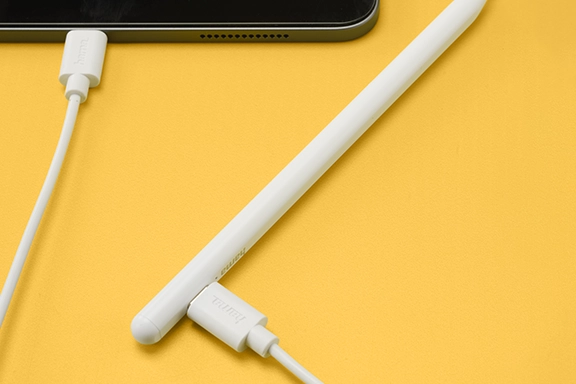 A tablet lies on a yellow background in the top left-hand corner, connected to the Hama ‘Scribble’ tablet pen with a USB-C cable and charging its battery.