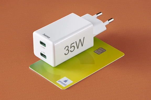 The Hama quick charger is placed on a debit card, which makes it clear how small the charger is.