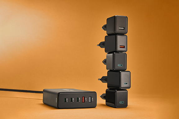The 5-way charger is on the left against an orange background, with five individual chargers stacked next to it.