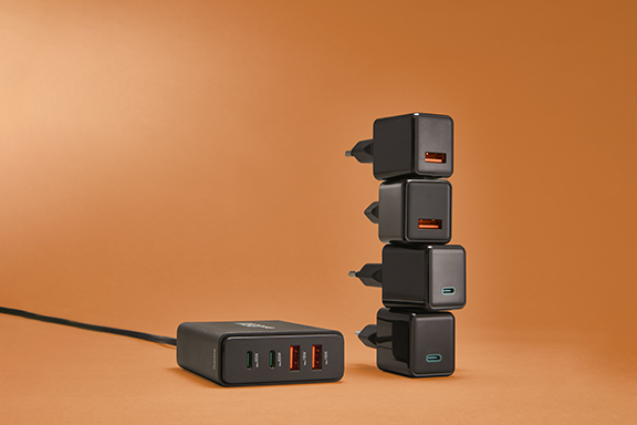 The quadruple charger is on the left against an orange background, with four individual chargers stacked next to it.