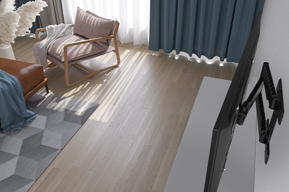 In a living room, a flat-screen TV is mounted on the wall on the swivel and extendable Hama TV wall mount
