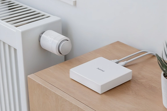 The Hama Smart Home Hub, Matter, Zigbee, Thread, for voice / app control is located on a sideboard right next to a radiator that is controlled with the Hama radiator thermostat.