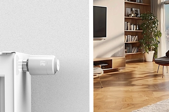 On the left side of the picture you can see the Hama thermostat on a radiator directly on the wall. In the background is a cosily furnished living room.